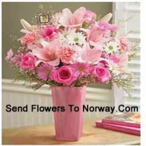 Roses roses, oeillets roses, gerberas roses, gerberas blancs et lys roses avec des remplisseurs saisonniers dans un vase en verre