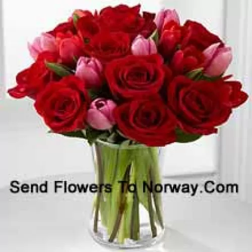11 rote Rosen und 6 rosa Tulpen mit einigen saisonalen Füllern in einer Glasvase